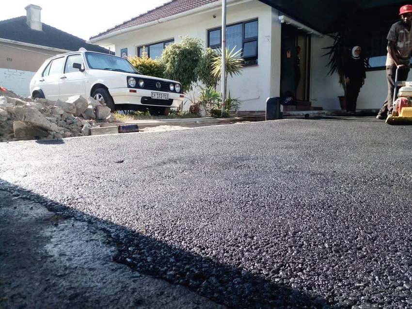 Residential driveway resurfacing in progress with compactor