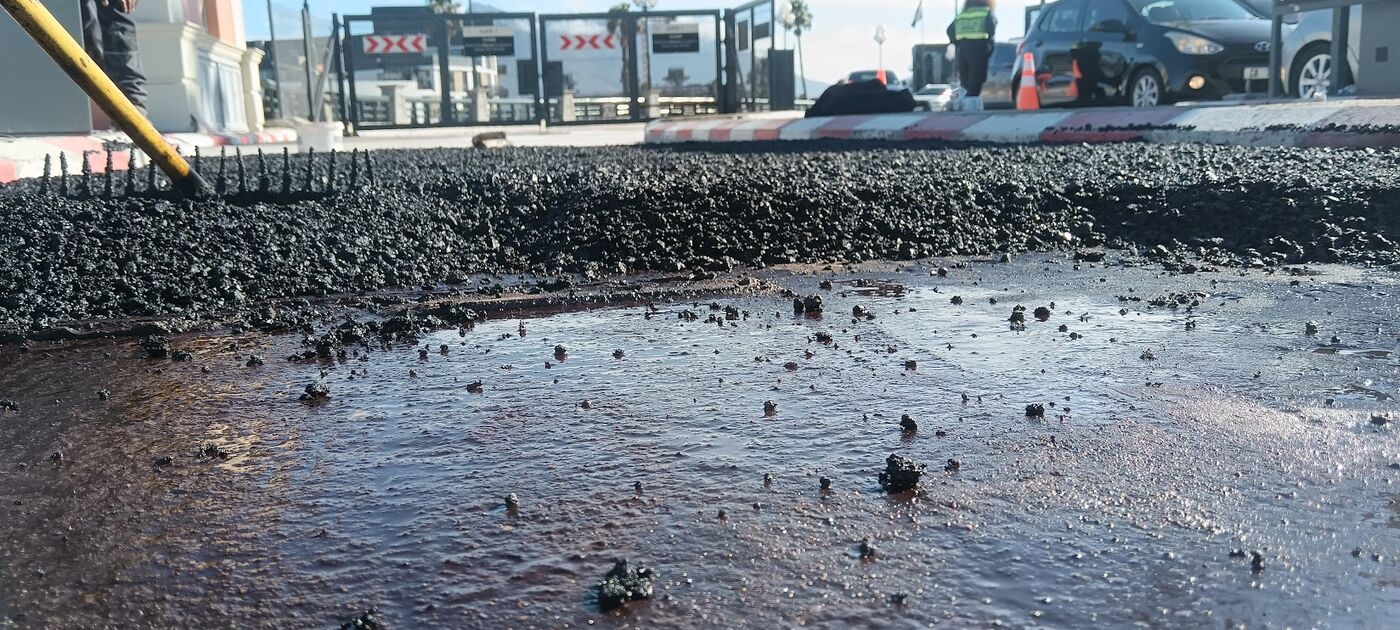 Close-up of hot asphalt being laid over tack coat