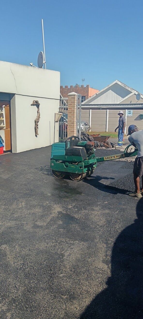 Compactor rolling freshly laid tar on a driveway