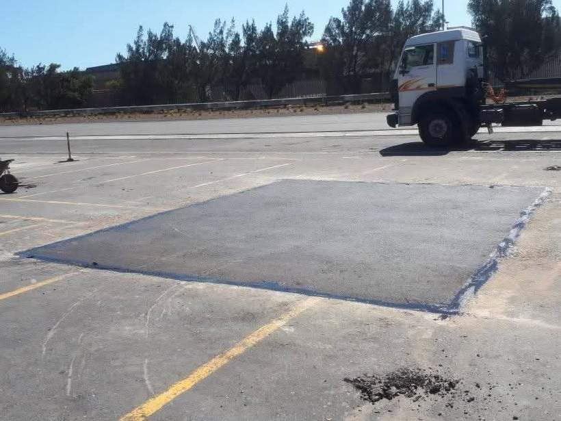 Repair area marked out in blue on worn concrete before patching